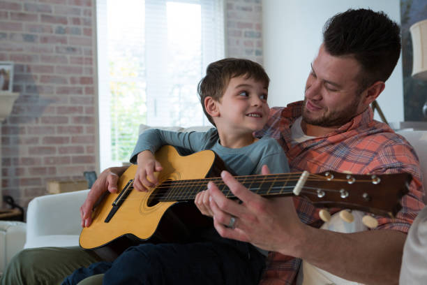 istock Father assisting his son in playing guitar 872844482
