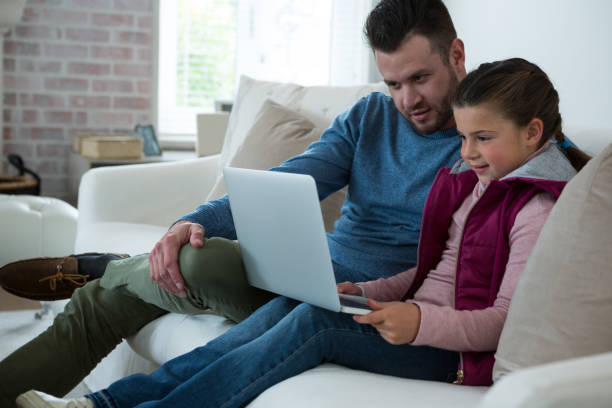 istock Father and daughter using laptop in living room 872844948