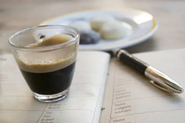 concept of business with an espresso coffee on a diary with money and a stylograph