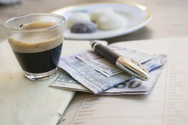 concept of business with an espresso coffee on a diary with money and a stylograph