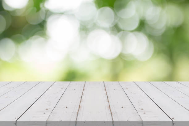 istock Empty white wood table top on nature green blurred background,space for montage show products 872852714