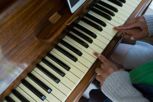 istock Mother assisting daughter in playing piano at home 872865726