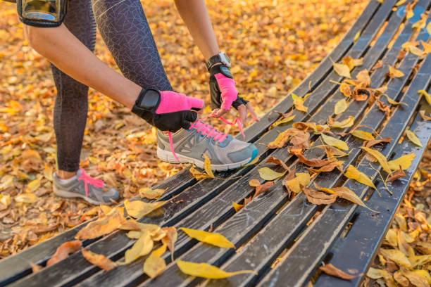istock female runner in forest tying shoe 872870122