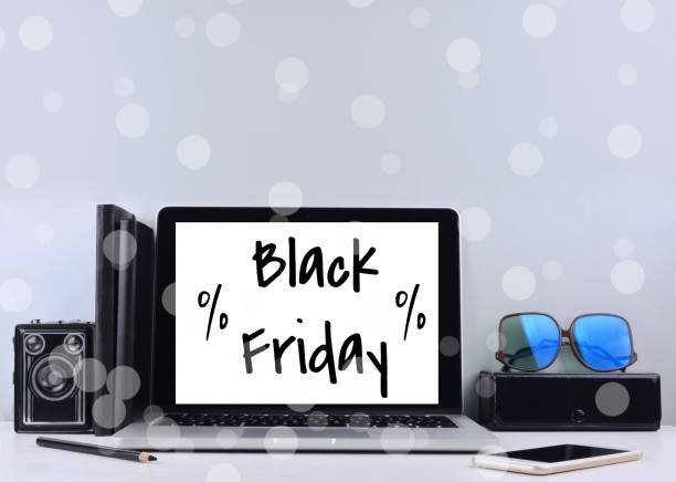 istock Open laptop with isolated white screen on white wooden desk with text black friday. 872877782