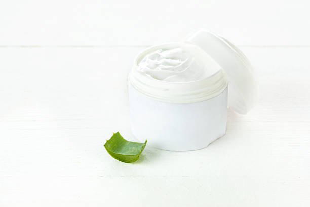 istock Opened plastic container with cream and aloe on a white background 872892538
