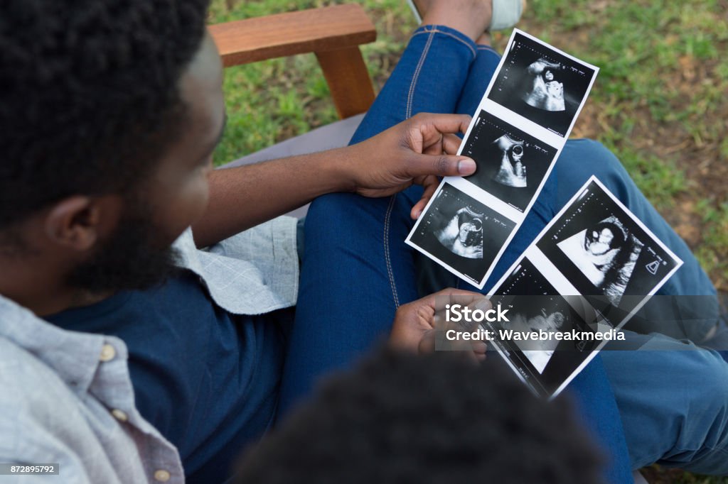 Couple looking at sonography in park Overhead of couple looking at sonography in park Couple - Relationship Stock Photo