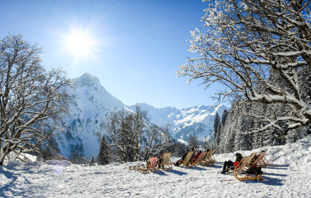 gruppe von personen, die mit liegestühlen im winterberge sitzen. ein sonnenbad im schnee. deutschland, bayern, allgäu, schwarzenberghuette. - apres ski snow winter european alps stock-fotos und bilder