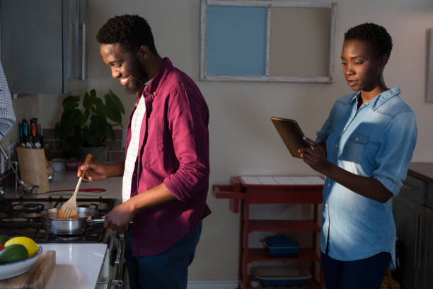 Woman digital tablet while man cooking in kitchen