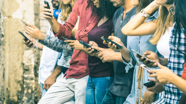 grupo de amigos multiculturales utilizando smartphone al aire libre - manos de las personas adictas por profundidad teléfono inteligente móvil - concepto de tecnología con conectados hombres y mujeres - de campo en tono filtro vintage - adicto grupo de jóvenes amigos usando teléfonos móviles fotografías e imágenes de stock