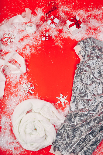 Festive Christmas attributes and decorations on a red background. Gift boxes and sequin dress on the snow.