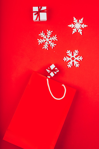 Festive Christmas presents on a red background with decorative snowflakes. Red paper package.