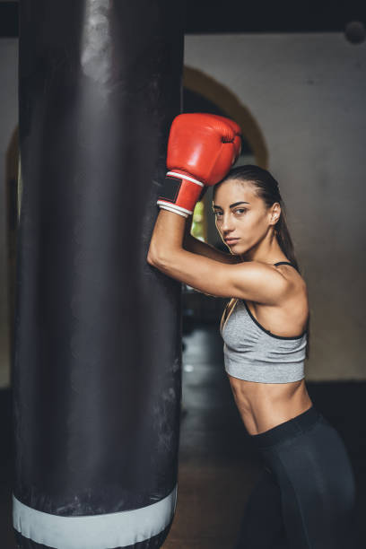 istock female boxer with punching bag 872916694