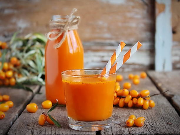 Homemade fresh sea buckthorn juice Homemade buckthorn soft drink in a glass and ripe sea buckthorn berries on the table. Healthy and diet food pics of a spiky fruit stock pictures, royalty-free photos & images
