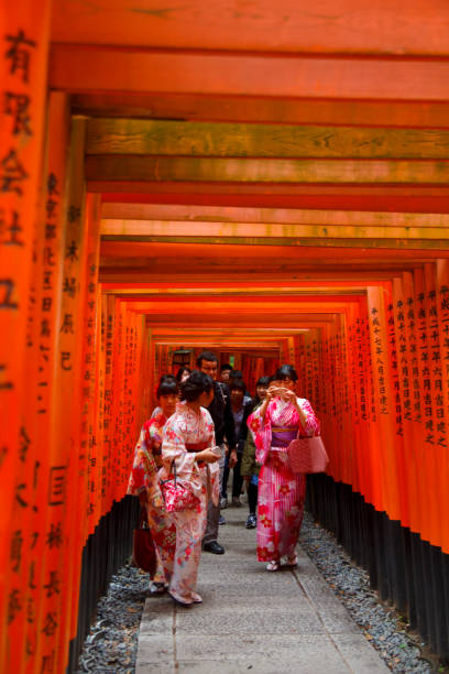 KYOTO, JAPAN - OCTOBER 13, 2017. Young women dressed in traditional Kimono in Fushimi Inari,  a path up to the mountain with many smaller shrines