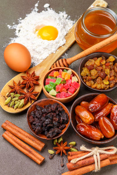 istock Baking a fruitcake. The ingredients on the table - dark and light raisins, dates, flour, eggs, honey, cinnamon, star anise, cardamom, candied fruit, orange. Traditional holiday pastries. Christmas. New year. Selective focus 872957584
