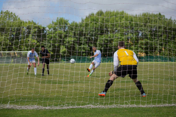 istock Soccer player kicking ball towards goal post 872969008