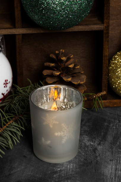 brennende kerze im leuchter und weihnachten attribute auf einem dunklen hintergrund - candle heat gold burning stock-fotos und bilder