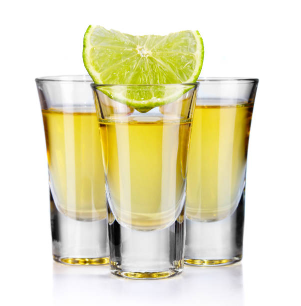 istock Three gold tequila shots with lime isolated on white 872980304