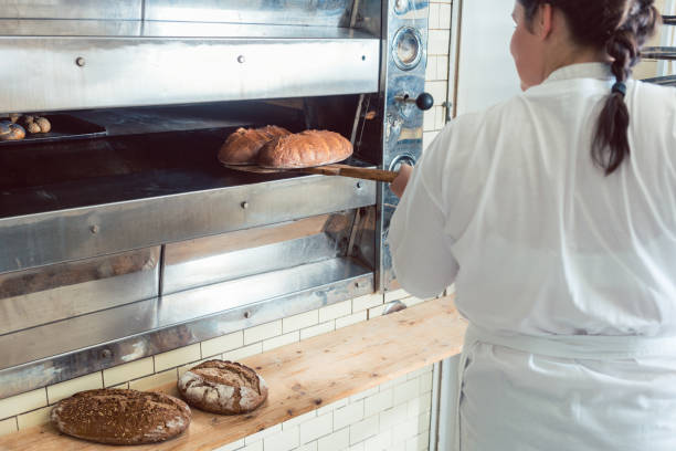 istock Baker getting fresh bread with shovel out of oven 872980782