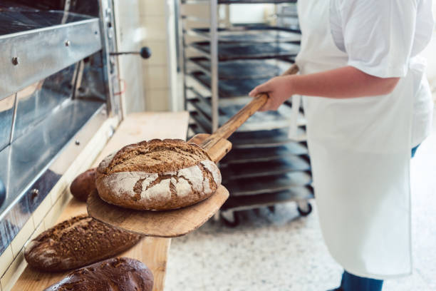 istock Woman in bakery putting bread on board 872998366