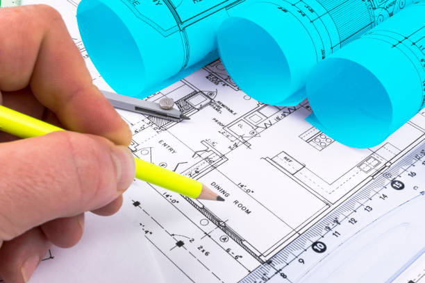 istock House Architectural blueprints and blueprint rolls and a drawing instruments on the worktable. Drawing compass, plans. Civil Engineering, Construction background. 873009044