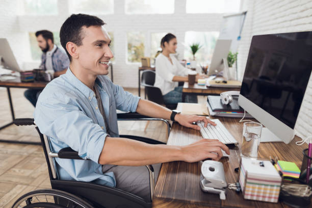 車椅子の障害者は、オフィス コンピューターで動作します。 - working people physical impairment wheelchair ストックフォトと画像