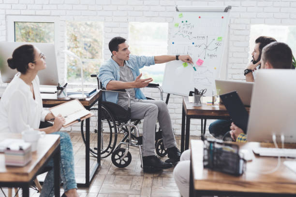 オフィス ワーカーと近代的なオフィスでビジネスの瞬間を議論する車椅子の人。 - working people physical impairment wheelchair ストックフォトと画像