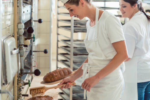 istock Team of two bakers preparing and coating bread 873016182