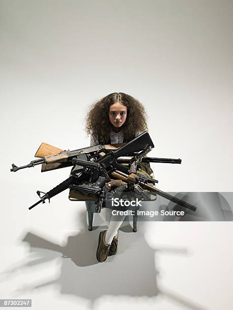 Girl With Guns On Desk ภาพสต็อก - ดาวน์โหลดรูปภาพตอนนี้ - กอง - การจัดวางตำแหน่ง, การควบคุมอาวุธปืน, การถ่ายภาพ - ภาพ