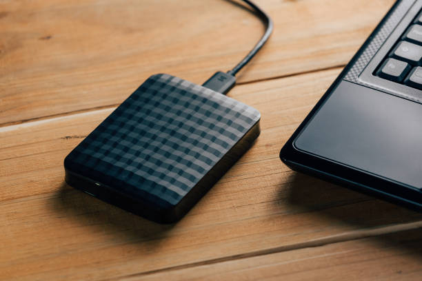 istock External hard drive connect to laptop computer on wooden background 873030330