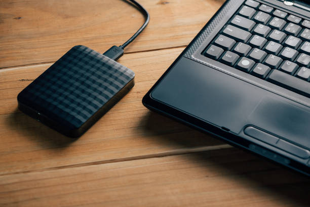 istock External hard drive connect to laptop computer on wooden background 873030870