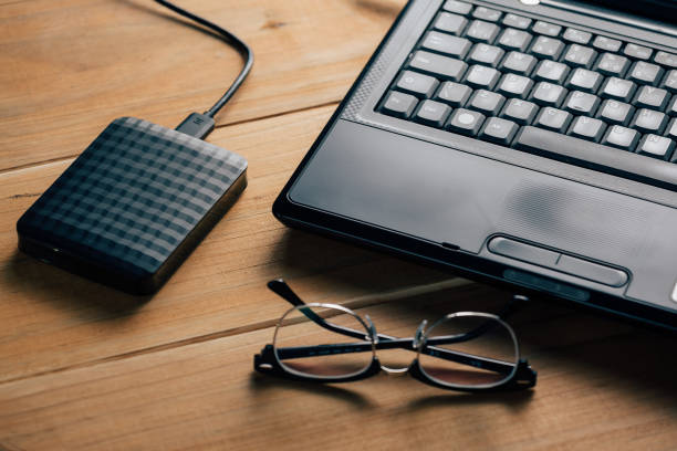 istock External hard drive connect to laptop computer on wooden background 873030950