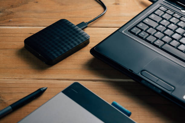 istock Laptop, external hard disk and graphic tablet on wooden background. 873030988