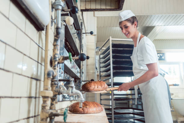 istock Baker woman getting bread out of bakery oven 873053758