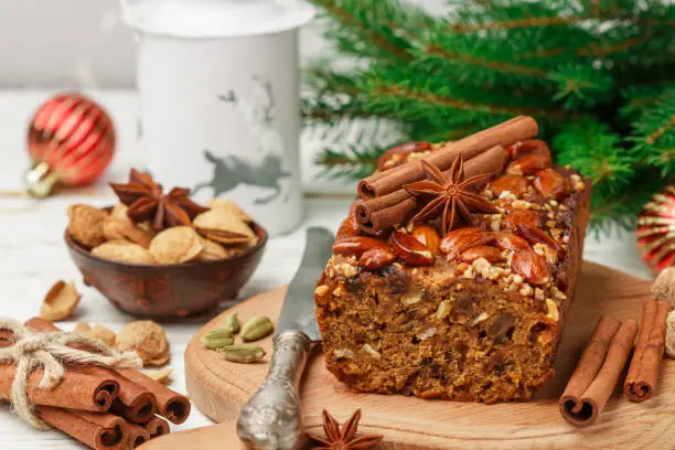 Homemade holiday Fruitcake with nuts, fruits and spices. Almonds, cinnamon, star anise, cardamom on the table. Traditional English pastries. Christmas. New year. Selective focus