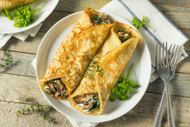 Savory Homemade Mushroom and Spinach Crepes Savory Homemade Mushroom and Spinach Crepes with Cheese crêpe pancake photos stock pictures, royalty-free photos & images