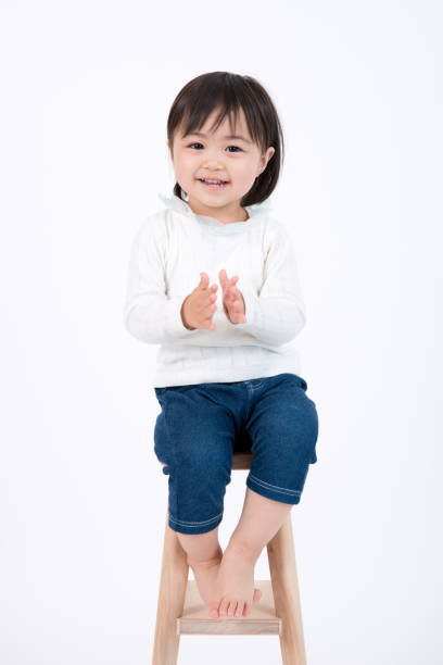portrait of smiling child family image on white background, without heavy processing but carefully and naturally retouched on skin clothing items and so on, very clean and neat image overall, photographed in ISO 100 girl sitting stock pictures, royalty-free photos & images