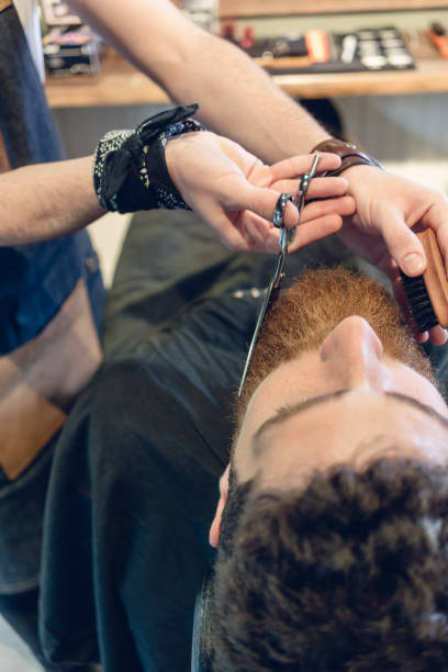 istock Close-up of the hand of a barber using scissors while trimming t 873081518