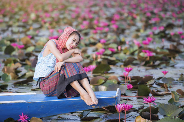 beautiful woman with lotus flower field at the red lotus sea picture of beautiful woman with lotus flower,young woman relaxing with beautiful lotus flower field at the red lotus sea, Bua Daeng, Udon Thani, Thailand udon thani stock pictures, royalty-free photos & images