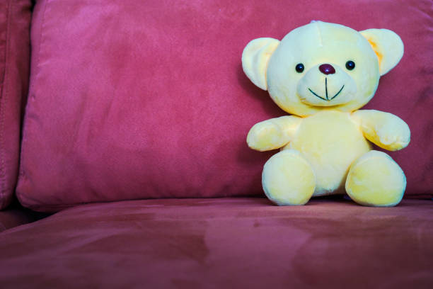 istock Yellow bear doll sitting on sofa, Couch with yellow bear doll sitting. 873091890
