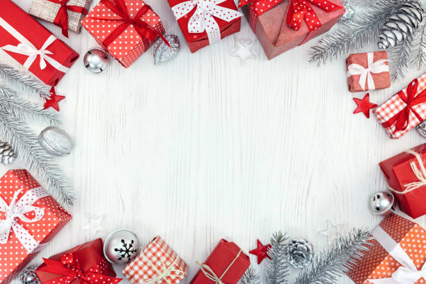 christmas gift boxes, decorations and silver fir tree branches on white wooden table