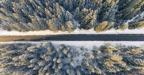 istock Black car on road in winter scenery, from above. 873117534