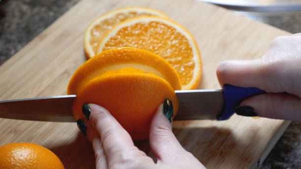 istock Female hands cutting orange on wooden board table in kitchen 873117882