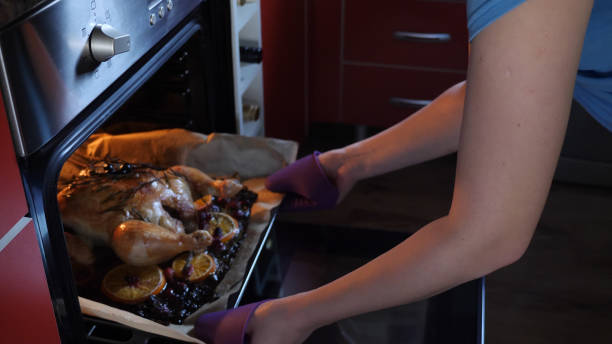 istock Female Hands Take Out Roasted Whole Chicken on tray From Hot Oven 873119372