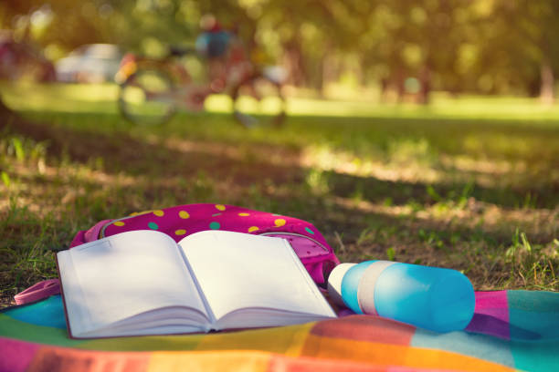 公園毛布書籍、リュックサック、ボトルの上に横たわる。背景に自転車 ストックフォト