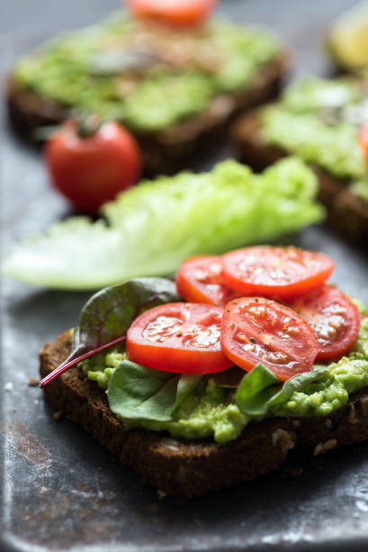 istock Vegan toast with avocado, spinach and tomato. Closeup view 873129994