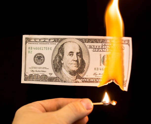 istock a hundred dollars burn in a fire on a black background 873131078