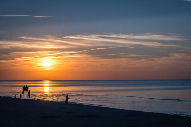 夏の日没でビーチを歩く人々 - lifeguard orange nature beach ストックフォトと画像
