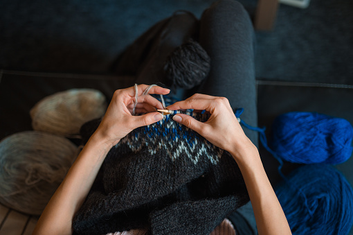 A woman knitting an Icelandic sweater in a cozy home