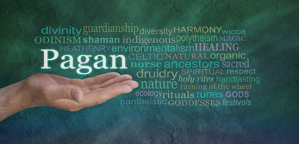 Male hand outstretched on a green stone effect background with the word PAGAN floating above surrounded by a relevant word cloud
